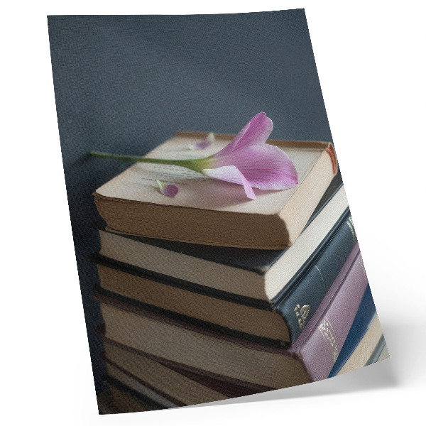 Hållbar väggposter En bunt böcker med en delikat blomma på toppen