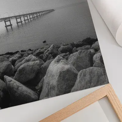 Hållbar väggposter fridfullt landskap med bro och stenig strand under en grå himmel