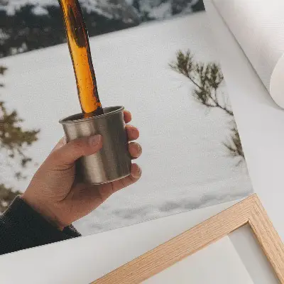 Affisch med motiv av en hand som bärnstenssubstans i ett bergigt snölandskap