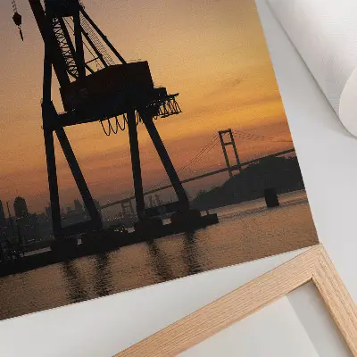 Hållbar väggposter industriell kran i silhuett mot en bro i solnedgång