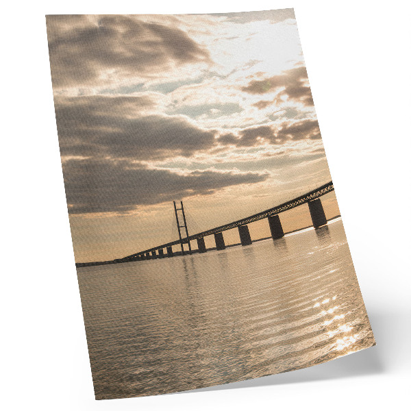 Poster En bro över vattnet i ljuset av den nedgående solen