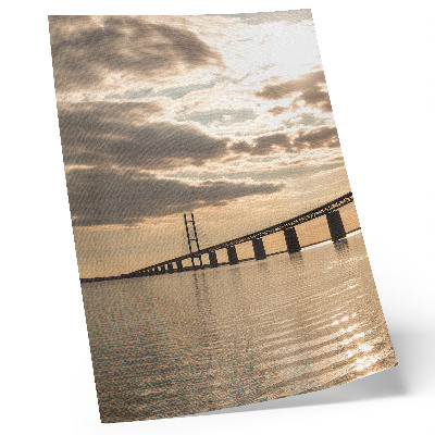 Poster En bro över vattnet i ljuset av den nedgående solen