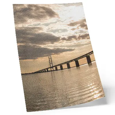 Poster en bro över vattnet i solnedgången