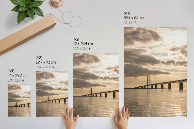 Poster En bro över vattnet i ljuset av den nedgående solen