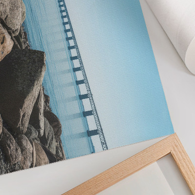 Stilren väggposter Bro över blå vattenstenar på stranden