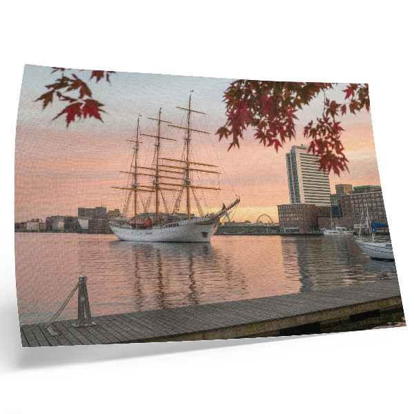 Väggposter Ett segelfartyg vid solnedgången, ett fridfullt panorama över staden