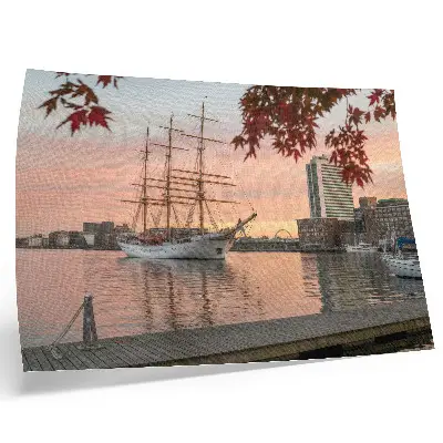 Väggposter ett segelfartyg vid solnedgången med ett fridfullt panorama över staden