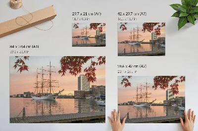 Väggposter Ett segelfartyg vid solnedgången, ett fridfullt panorama över staden