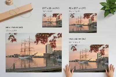 Väggposter ett segelfartyg vid solnedgången med ett fridfullt panorama över staden