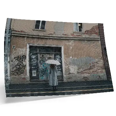 Poster en person med paraply framför en graffitivägg