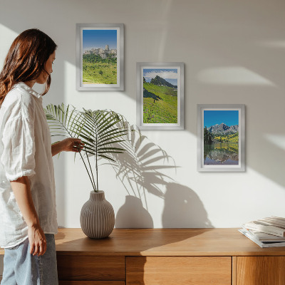 Tavelvägg med 3 tavlor Gröna kullar med ett slott och bergslandskap