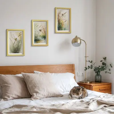 Tavelvägg med 3 tavlor med motiv av trollsländor bland gräset vid vattnet i målerisk stil