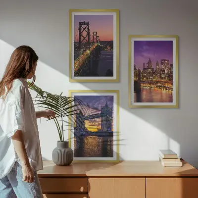 Tavelset ovanför soffa med motiv av broar, sol och stadsutsikt