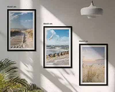 Tavelset ovanför soffa med motiv av strand, sand, vågor, himmel och fåglar