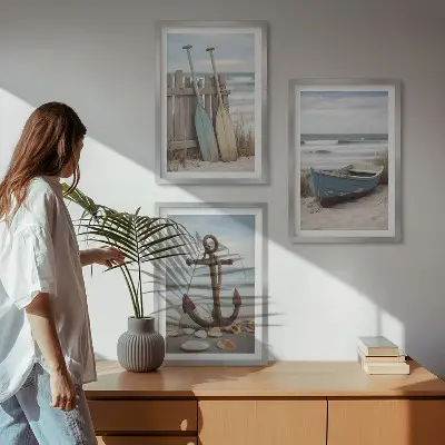 Tavelset ovanför soffa med motiv av strand, båt, ankare och sand