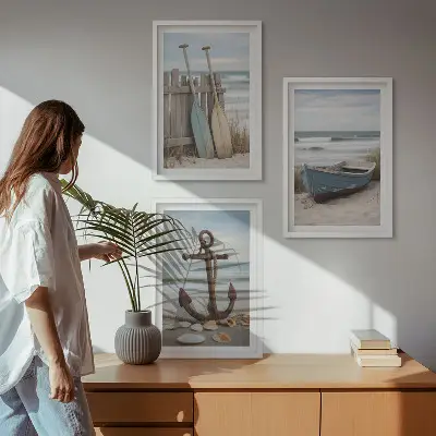 Tavelset ovanför soffa med motiv av strand, båt, ankare och sand