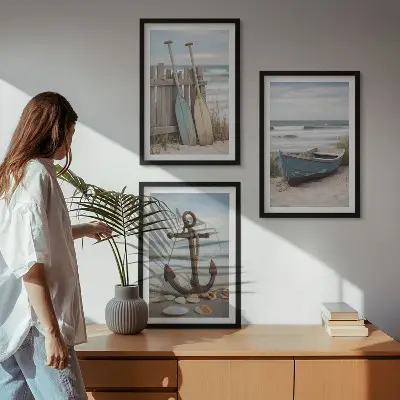 Tavelset ovanför soffa med motiv av strand, båt, ankare och sand