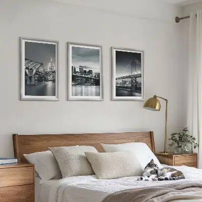 Tavelset ovanför soffa med motiv av broar och stadsarkitektur i grå toner
