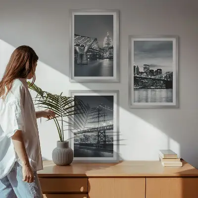 Tavelset ovanför soffa med motiv av broar och stadsarkitektur i grå toner