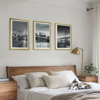 Tavelset ovanför soffa med motiv av broar och stadsarkitektur i grå toner
