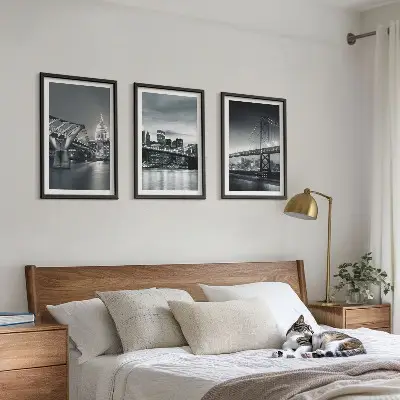 Tavelset ovanför soffa med motiv av broar och stadsarkitektur i grå toner