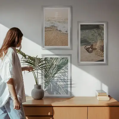 Tavelset ovanför soffa motiv med vatten, strandhatt och solglasögon