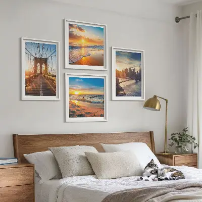 Tavelvägg ovanför soffa med motiv av broar i solnedgång över stad