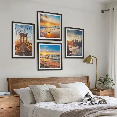Tavelvägg ovanför soffa med motiv av broar i solnedgång över stad