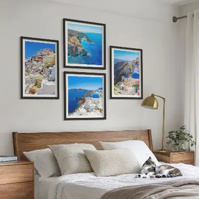 Tavelvägg ovanför soffa med motiv av arkitektoniskt landskap i Oia på Santorini