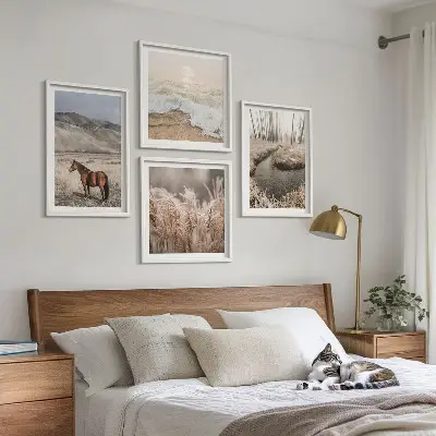 Tavelvägg ovanför soffa med motiv av hästar i ett landskap med sjögräs och skog