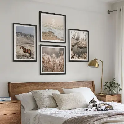 Tavelvägg ovanför soffa med motiv av hästar i ett landskap med sjögräs och skog