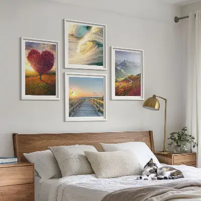 Tavelvägg ovanför soffa med motiv av landskap med berg, vågor, träd, hjärta och pir