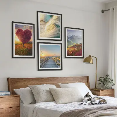 Tavelvägg ovanför soffa med motiv av landskap med berg, vågor, träd, hjärta och pir