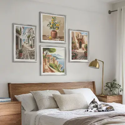 Tavelvägg ovanför soffa med motiv av gator, hus, växter och krukor