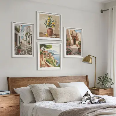 Tavelvägg ovanför soffa med motiv av gator, hus, växter och krukor