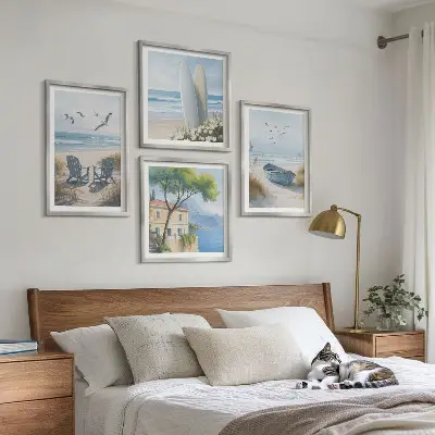 Tavelvägg ovanför soffa med motiv av strandbrädor, surfbåt och fåglar