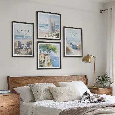 Tavelvägg ovanför soffa med motiv av strandbrädor, surfbåt och fåglar