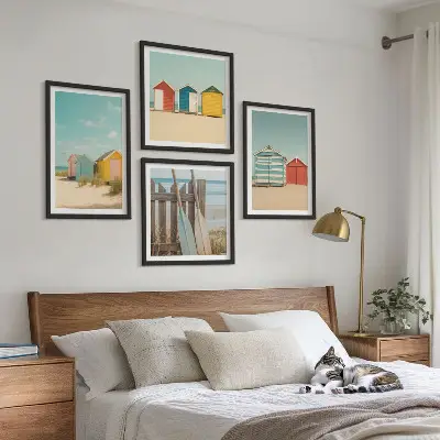 Tavelvägg ovanför soffa färgglada hus, strand och sol