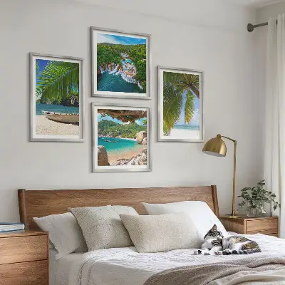 Tavelvägg ovanför soffa med motiv av strand, båt, vattenfall och palmer