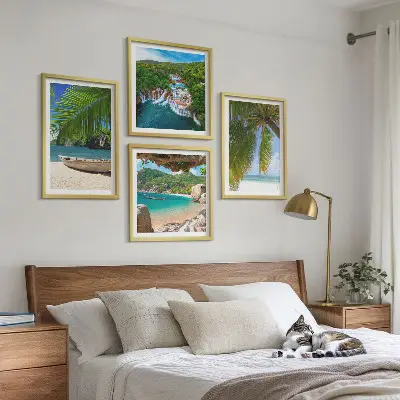Tavelvägg ovanför soffa med motiv av strand, båt, vattenfall och palmer
