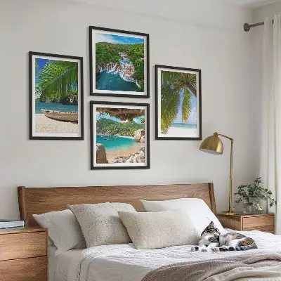 Tavelvägg ovanför soffa med motiv av strand, båt, vattenfall och palmer
