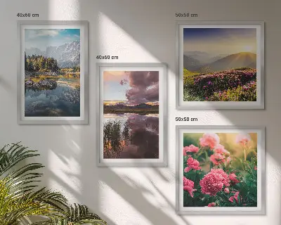Tavelvägg ovanför soffa med motiv av blommor, trädgård, berg, äng och vatten