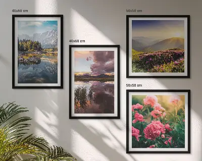 Tavelvägg ovanför soffa med motiv av blommor, trädgård, berg, äng och vatten