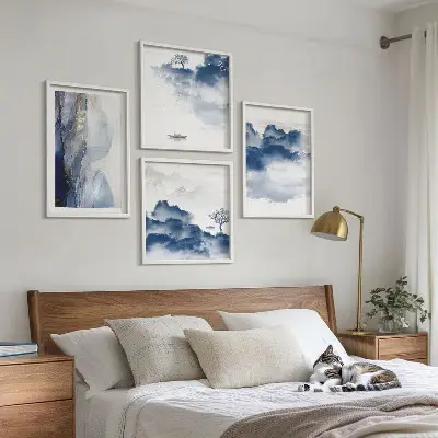 Tavelvägg ovanför soffa med berg, moln, träd och fåglar