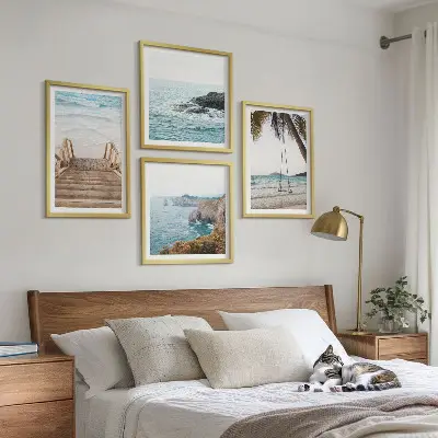 Tavelvägg ovanför soffa med motiv av trappor vid havet och en gunga