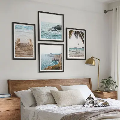 Tavelvägg ovanför soffa med motiv av trappor vid havet och en gunga
