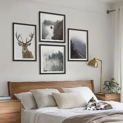 Tavelvägg ovanför soffan med motiv av bergslandskap med dimma och rådjur