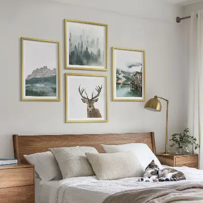 Tavelvägg med motiv av berg, sjö, rådjur, hydda och dimma ovanför soffan